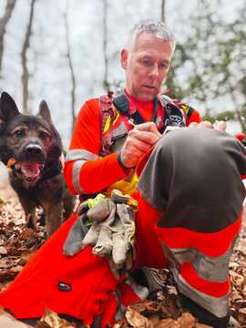 Reševalec preverja koordinate na terenu, poleg njega reševalni pes
